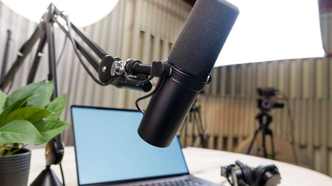 Podcast-studion mikrofoni, kannettava tietokone ja kuulokkeet työpöydällä